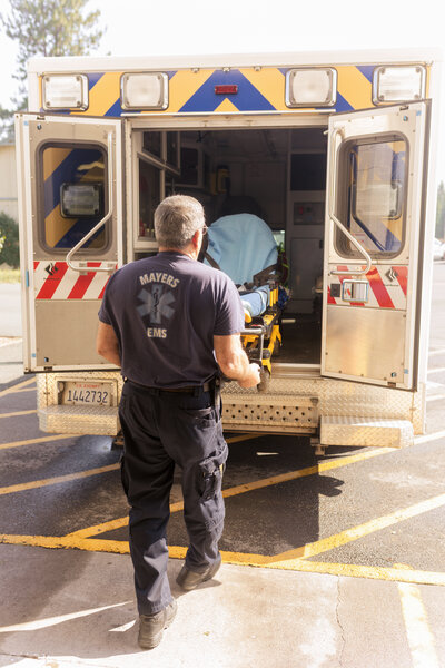 Male ENT loading a gurney into an ambulance truck. 